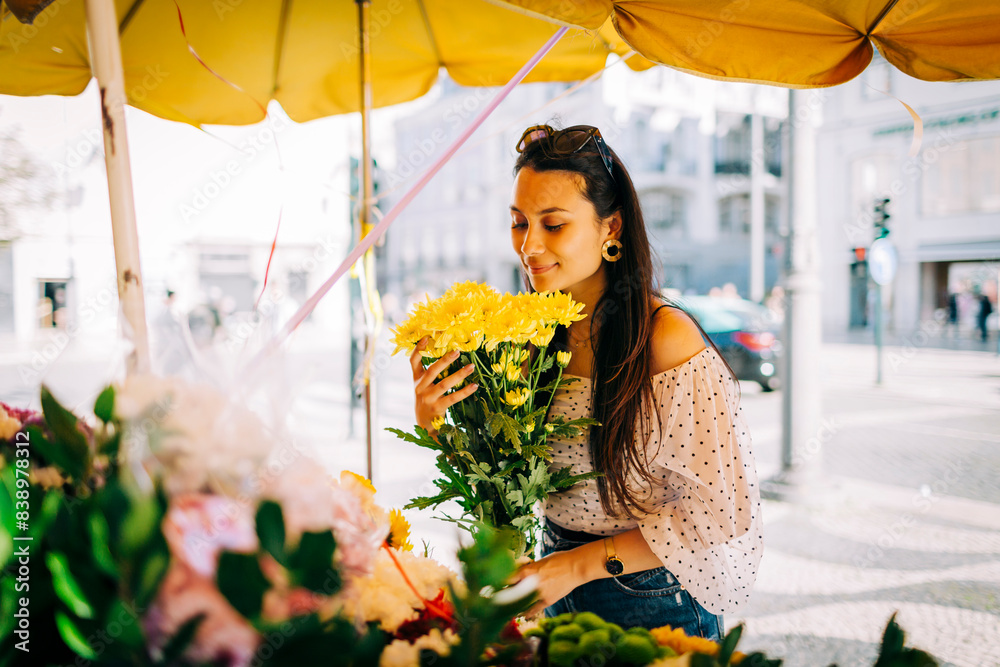 Young woman smelling bouquet of flowers at flower shop