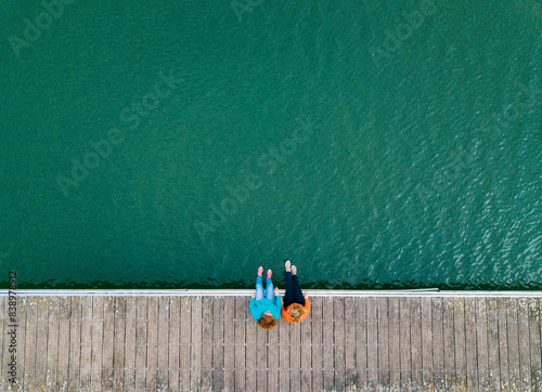 Obraz na płótnie Two friends sitting side by side on jetty, Valdemurio Reservoir, Asturias, Spain w salonie