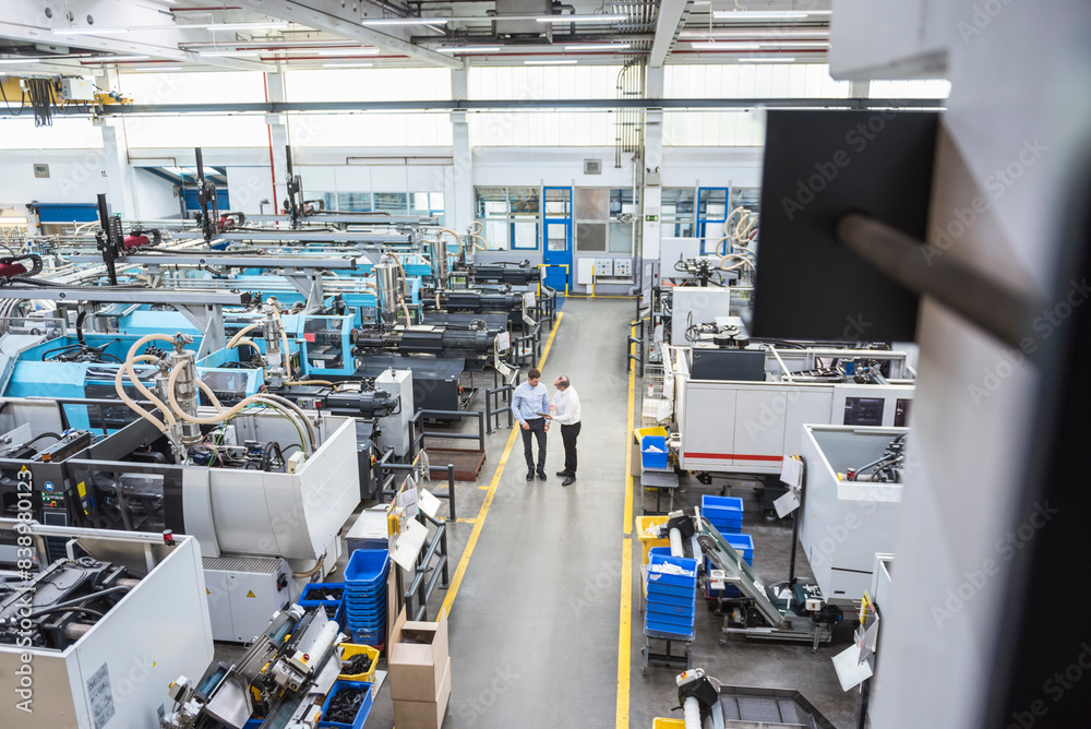 Two men with tablet talking in factory shop floor