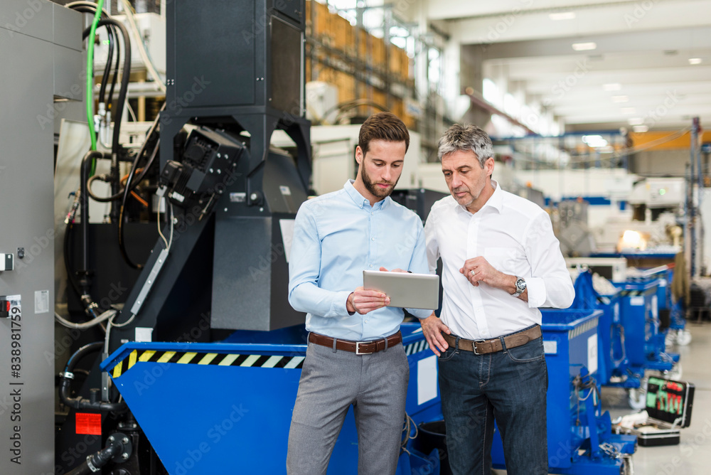 Businessmen using tablet during meeting in production hall
