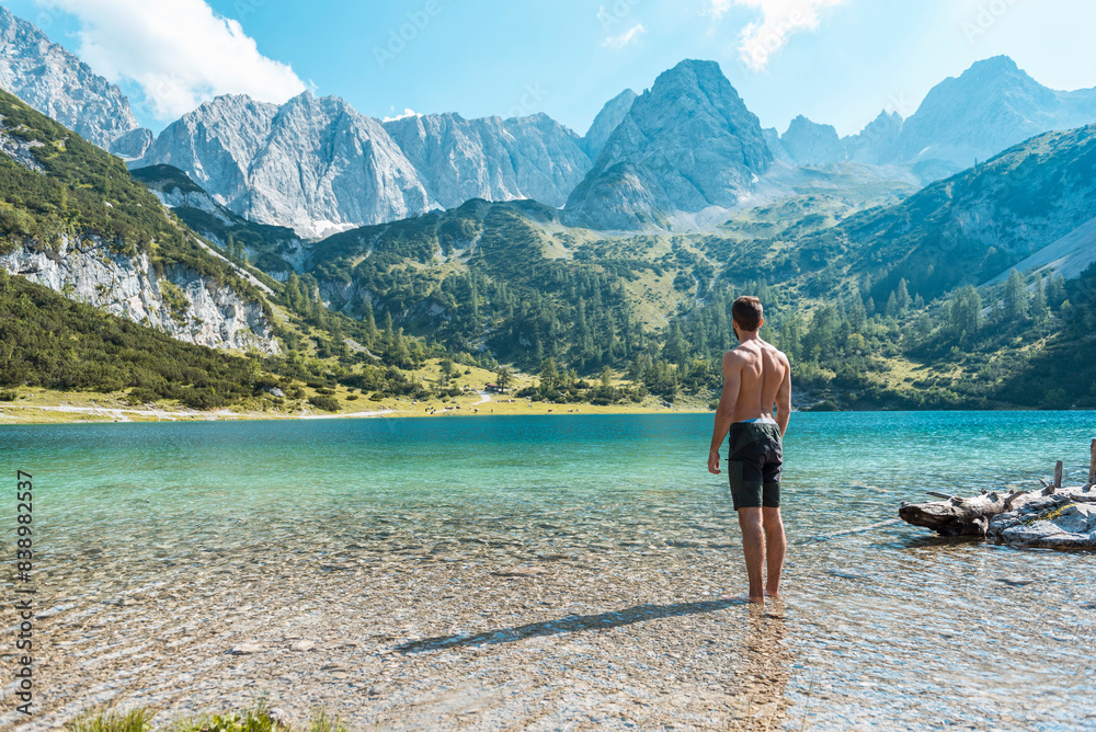 Austria, Tyrol, Young man at Lake Seebensee standing ankle deep in water