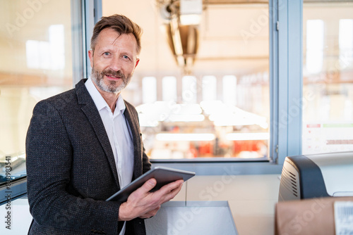 Obraz na płótnie Portrait of businessman using tablet at the window with factory background w salonie