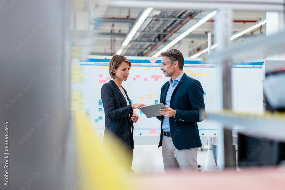 Businessman and businesswoman talking in a factory hall