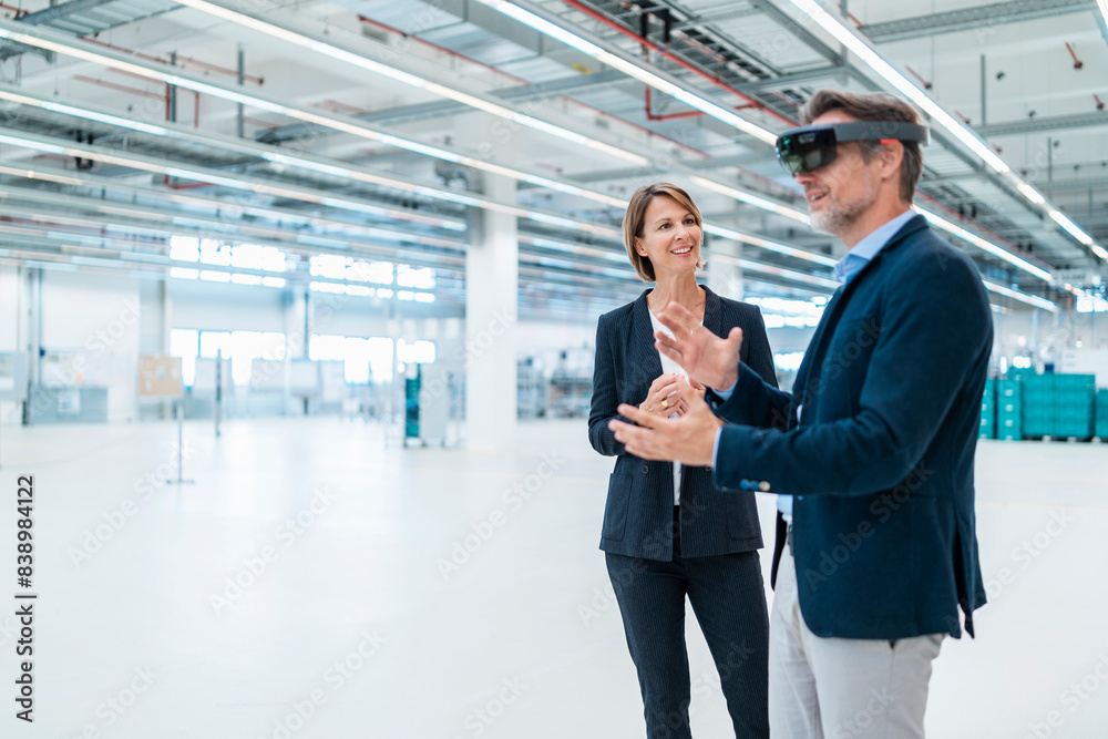 Businessman with AR glasses and businesswoman in a factory hall