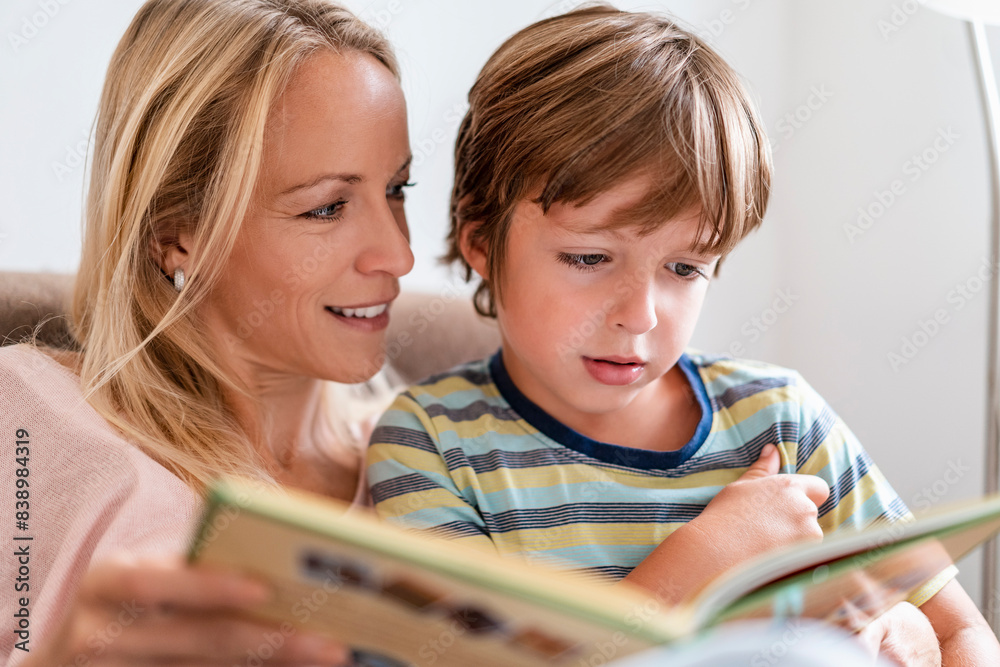 Mother and son reading a book together on couch at home Mother and son reading a book together on couch at home