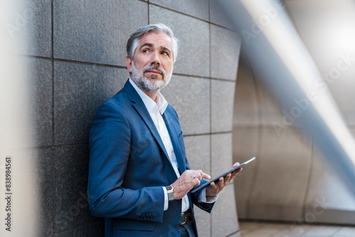 Obraz na płótnie Mature businessman standing at a wall using tablet w salonie