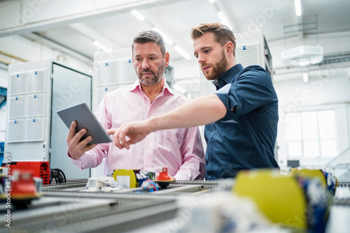Two men with tablet having a work meeting in a factory