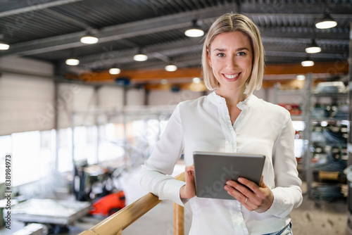 Portrait of smiling young woman using tablet in a factory
