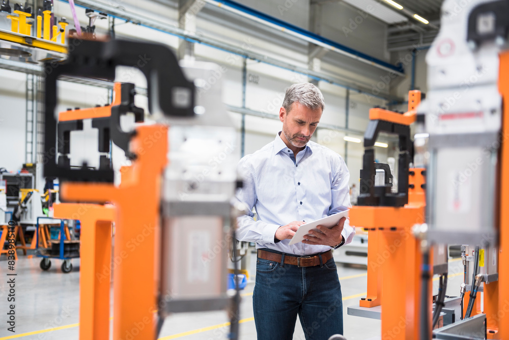 Mature man using tablet on factory shop floor