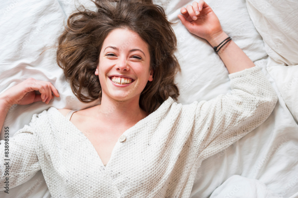 Cheerful young woman lying in bed at home Cheerful young woman lying in bed at home