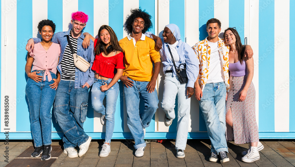 Obraz premium Multiethnic group of young happy friends hanging out in the city - Multiracial group of students meeting and having fun outdoors, concepts about youth, teenage, diversity and lifestyle