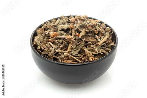 Close-up of Dry Organic Ashwagandha (Withania somnifera) leaves, in black ceramic bowl. Isolated on a white background. photo