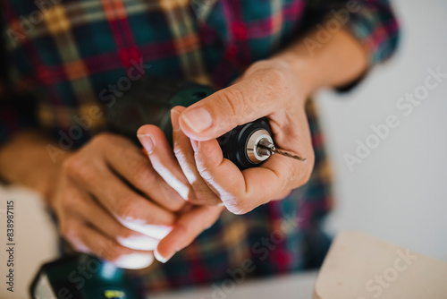 Close-up of woman holding chuck of electric drill while standing at home photo