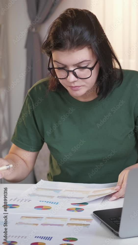 Vertical video. Data analytics. Account manager. Busy hardworking woman analyzing market graphs at laptop desk home workplace.