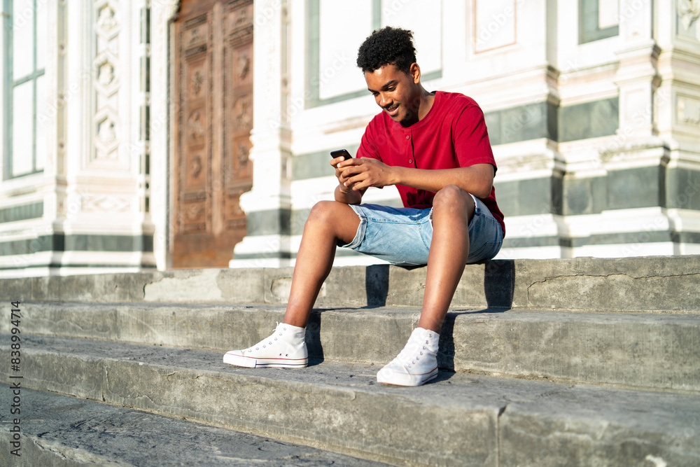 Young man sitting on outdoor stairs checking his smartphone, Florence, Italy Young man sitting on outdoor stairs checking his smartphone, Florence, Italy