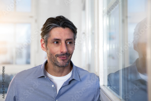 Smiling man in office looking out of window