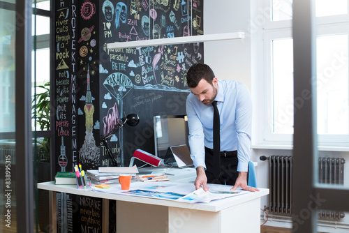 Businessman at desk in office looking at printouts