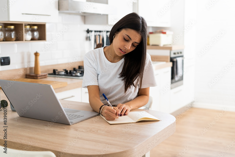 Young woman with laptop taking notes at home Young woman with laptop taking notes at home