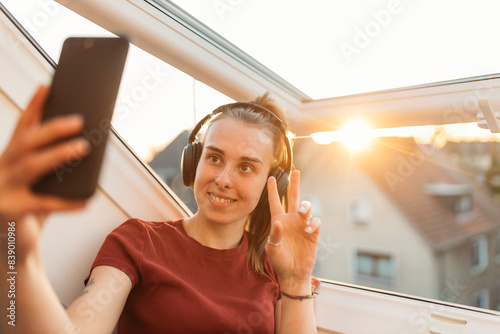 Young woman having a video chat at the window in backlight photo