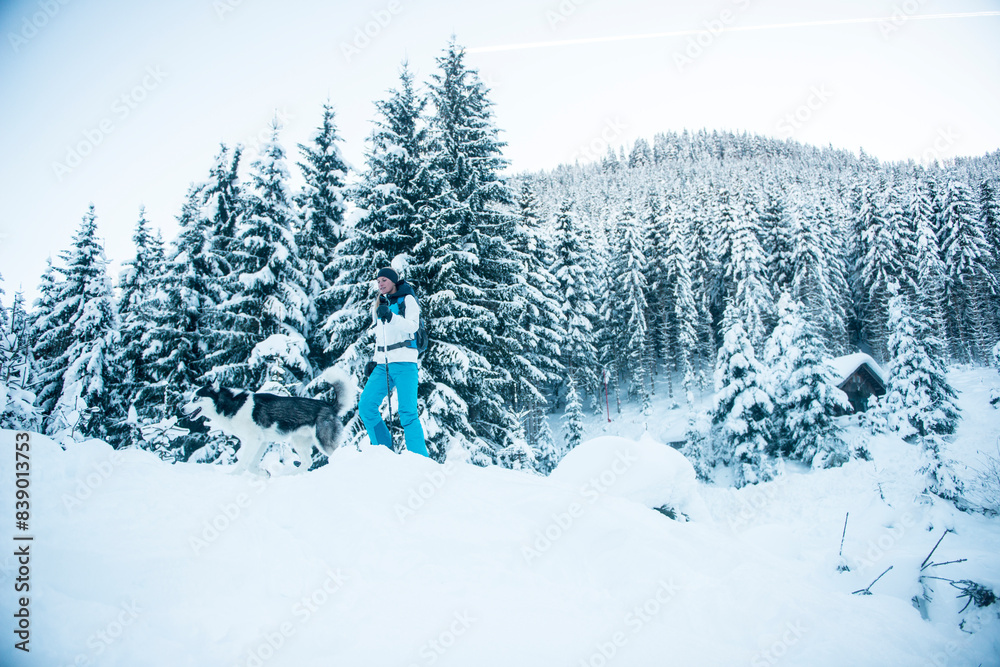 Fototapeta premium Austria, Altenmarkt-Zauchensee, young woman with dog in winter forest