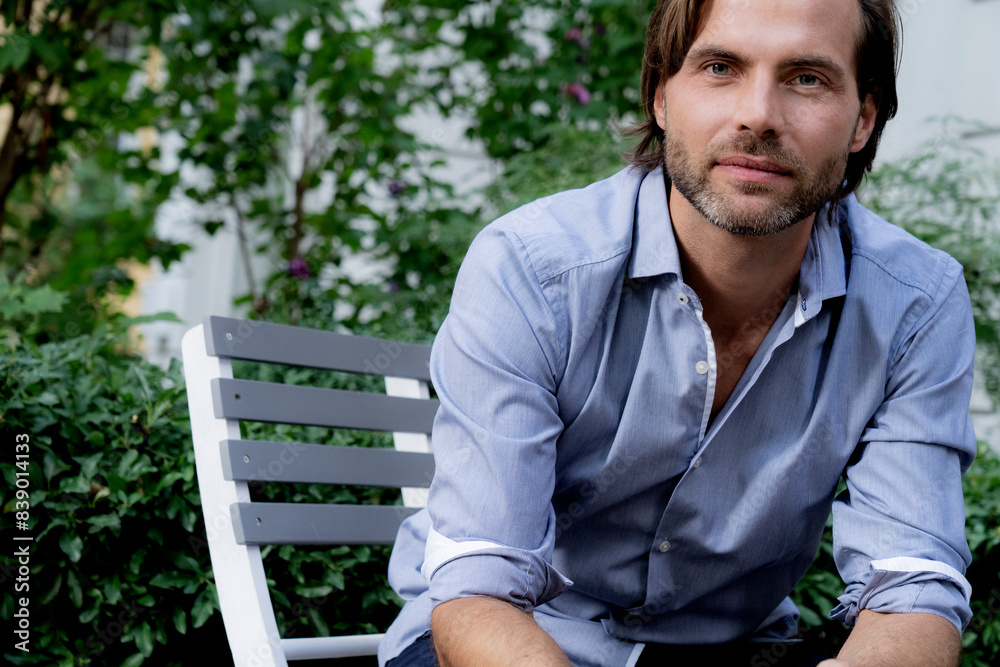 Portrait of confident man sitting on chair in garden Portrait of confident man sitting on chair in garden