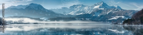 A misty mountain lake  its surface calm and reflective  mirroring the snow-capped peaks that rise around it.