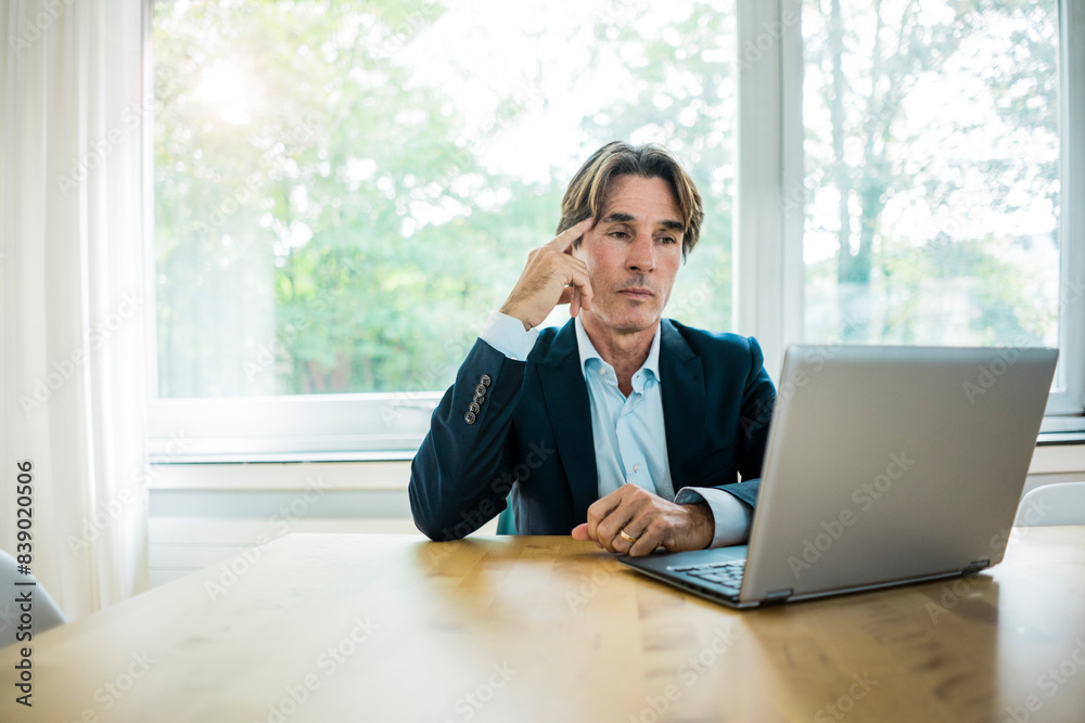 Businessman using laptop at table in office Businessman using laptop at table in office