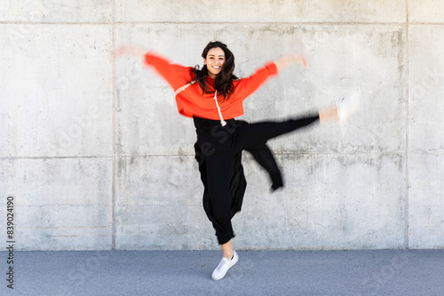 Young contemporary dancer wearing red hoodie shirt in front of a wall © tunedin