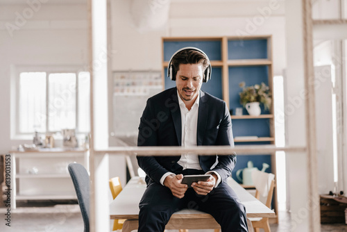 Businessman with tablet and headphones sitting on table photo