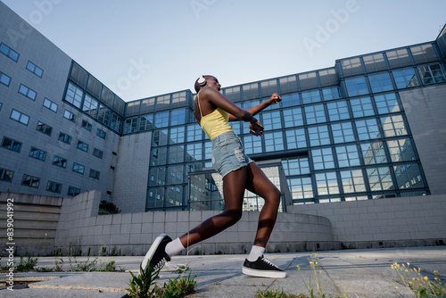 Young woman dancing on footpath against building in city