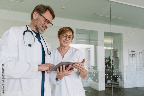 Doctor and assistant using tablet in medical practice photo