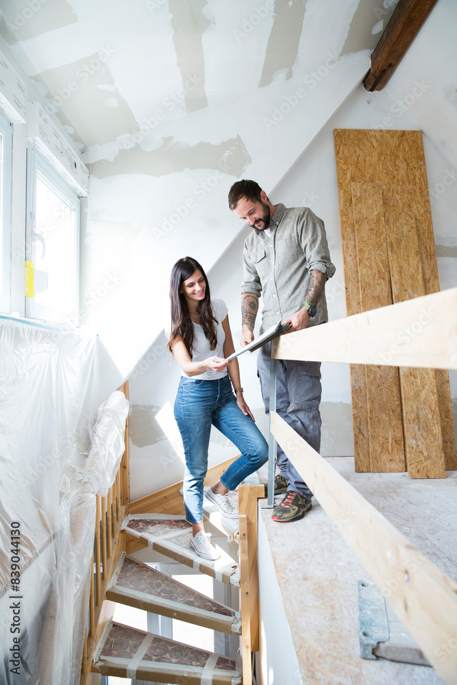Couple in attic to be renovated looking in catalgue