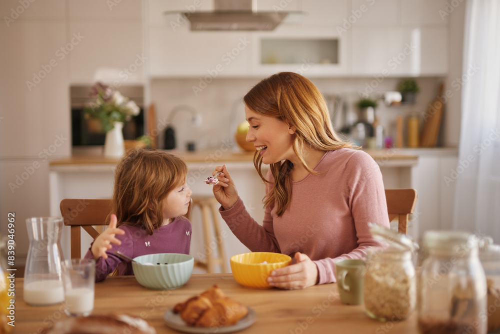 Mother having a breakfast with her little girl in the kitchen Mother having a breakfast with her little girl in the kitchen