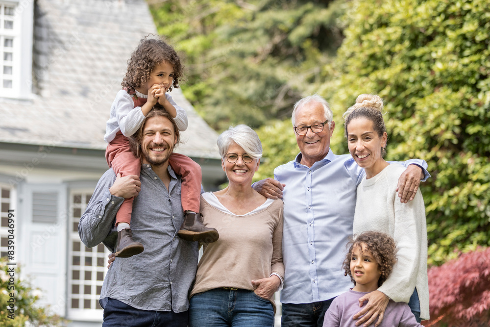 Happy extended family standing in garden of their home
