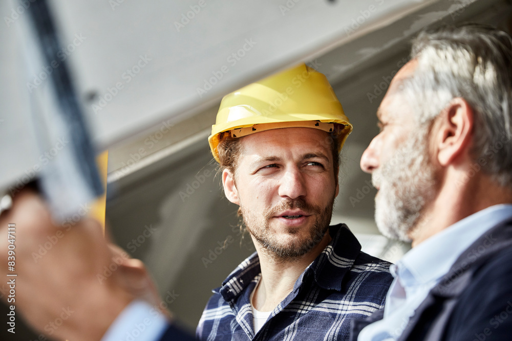 Architect and worker talking at the window on a construction site