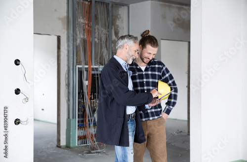 Architect and construction worker discussing over digital tablet while standing in renovating house © tunedin