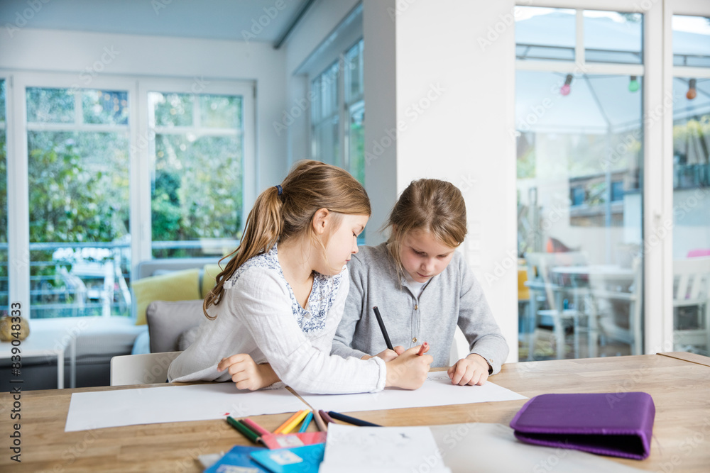 Two girls doing homework at table together