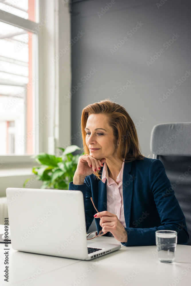 Businesswoman sitting in office, working on laptop Businesswoman sitting in office, working on laptop