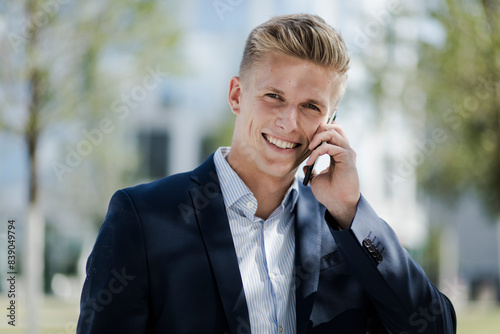 Portrait of smiling young businessman talking on cell phone