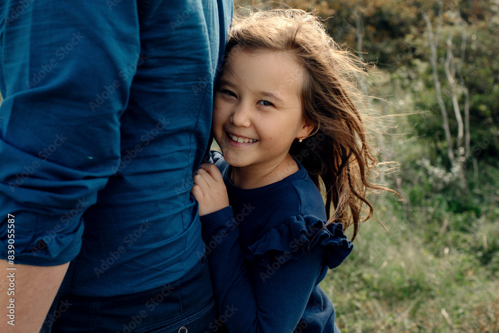 Portrait of laughing little girl hiding behind her father's back Portrait of laughing little girl hiding behind her father's back