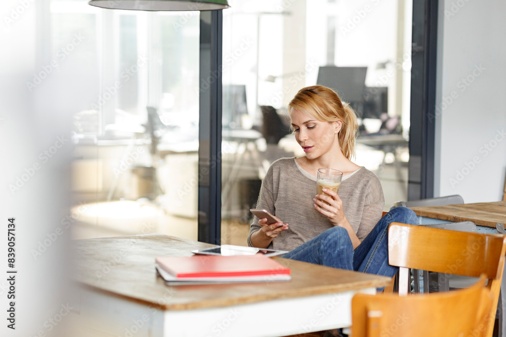 Woman checking cell phone in office Woman checking cell phone in office