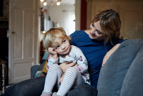 Mother and little daughter sitting together on the couch at home photo