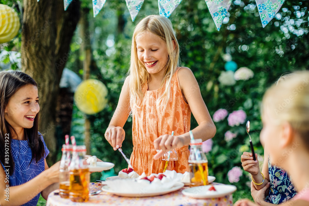 Girl dishing up cake on a birthday party outdoors Girl dishing up cake on a birthday party outdoors