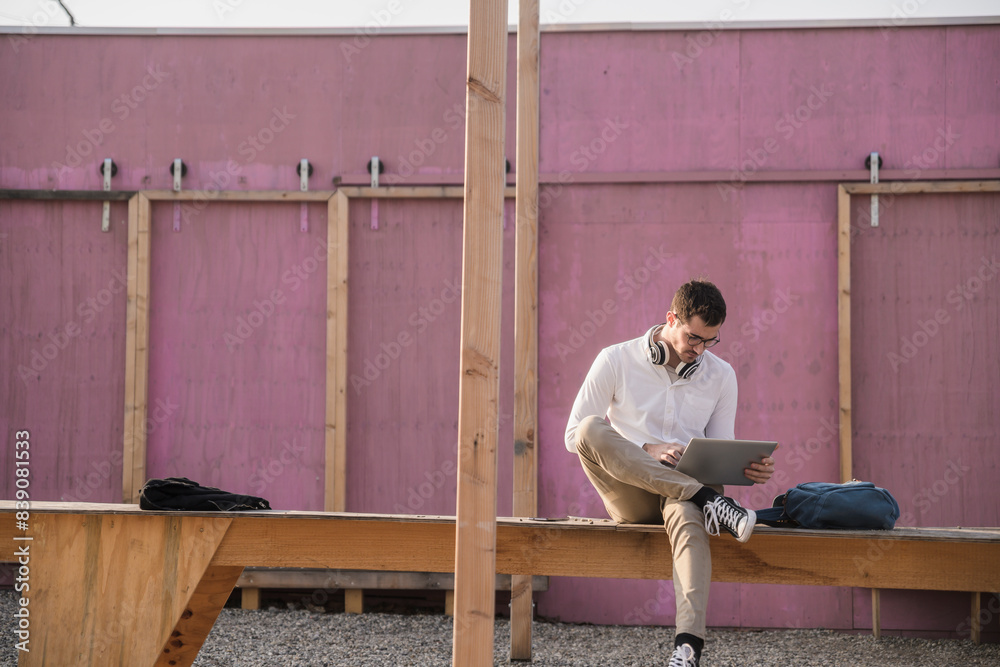 Young man sitting on platform using tablet