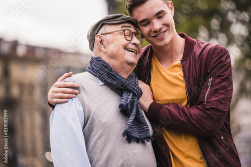 Happy senior man head to head with his adult grandson outdoors