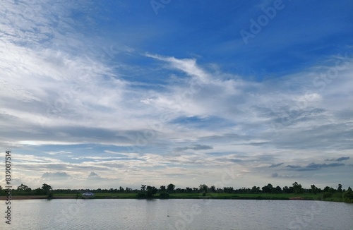 Beautiful cloudy sky at sunset reflected on rice fields water. Sunset river view. Calm waters reflect the vibrant hues of the sunset. trees silhouetted against the sky. countryside thailand summer