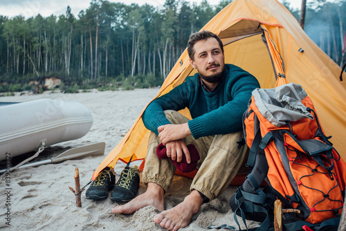 Backpacker sitting in front of his tent on the beach photo