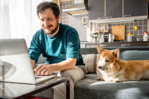 Obraz na płótnie Portrait of smiling man sitting on couch at home using laptop w salonie