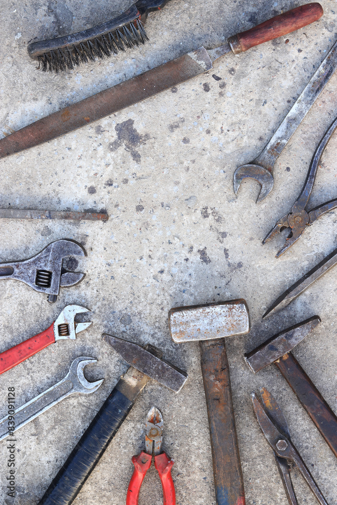 Old working tools on a concrete surface, top view. Hammers, flat file, tin snips, adjustable wrench and wrench. Hand tool. Builder's Day or Father's Day. Construction and renovation concept Old working tools on a concrete surface, top view. Hammers, flat file, tin snips, adjustable wrench and wrench. Hand tool. Builder's Day or Father's Day. Construction and renovation concept