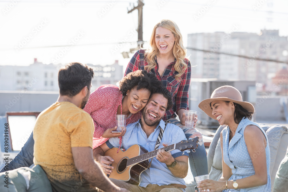 Friends having a rooftop party and playing guitar Friends having a rooftop party and playing guitar